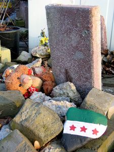 360px-2013-03-02_Gravestone_without_name_fallen_teddy_bear_symbolising_child_and_children_killed_by_war,_stone_with_painted_syrian_flag